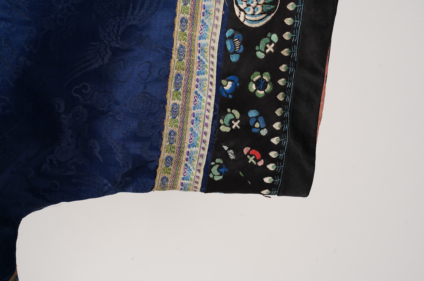 A late 19th century Chinese blue silk damask jacket, woven with Phoenix and auspicious symbols. The jacket edged with ornate rows of braiding and silk embroidery, the interior with original pink silk lining. The jacket f